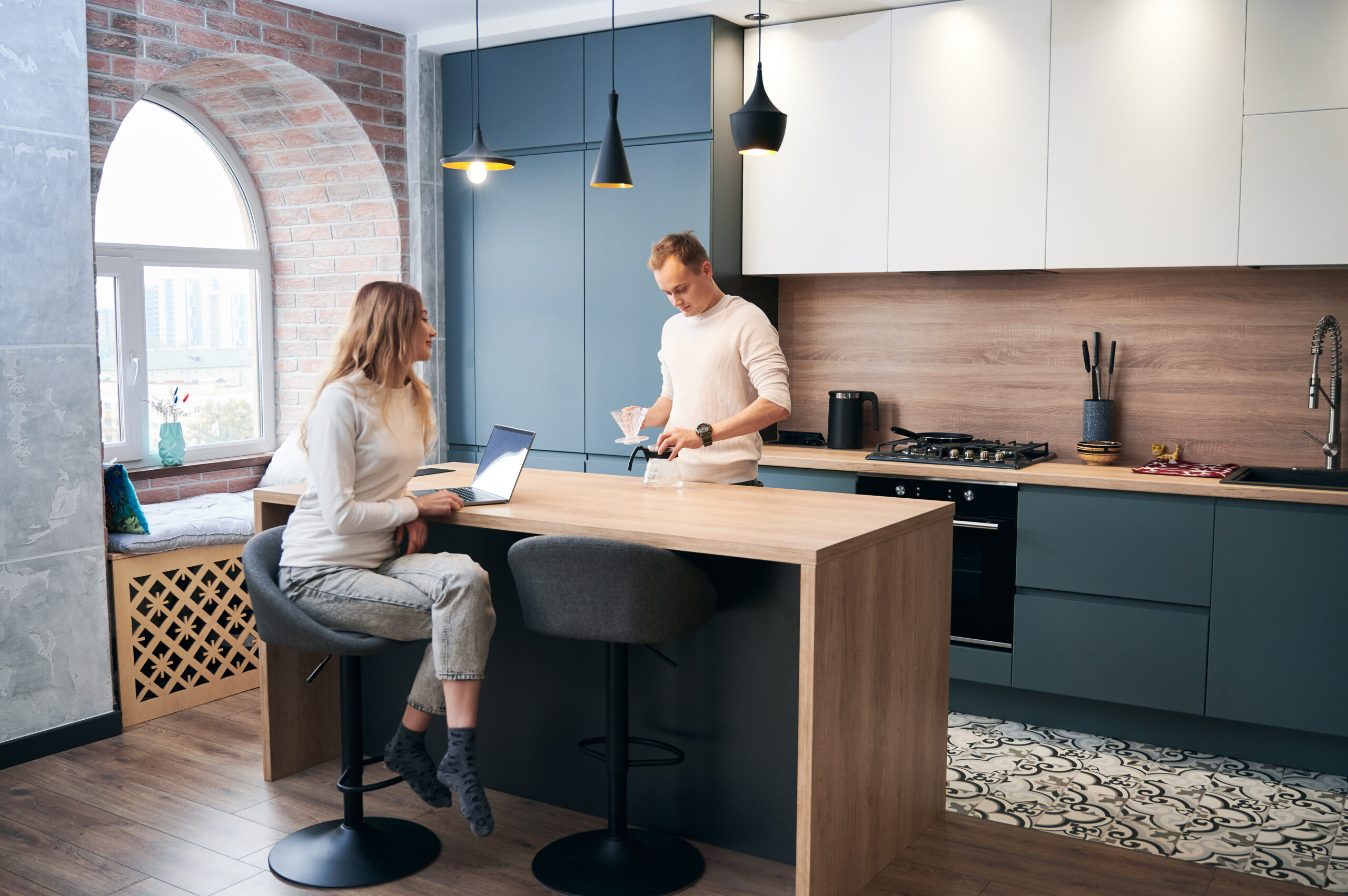 Woman and man working in laptop at home in modern kitchen.